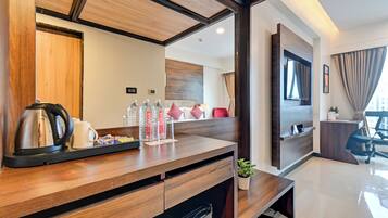 A modern hotel room with a wooden desk, a coffee maker, and bottled water.