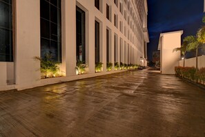 A long, narrow building with a wet floor, large windows, and plants along the walkway. - Hotel Tip Top International (Paud)