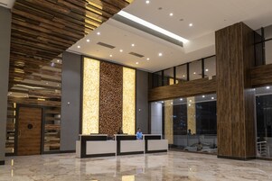 Un área de recepción moderna con un revestimiento de pared de madera, suelo de mármol y mostrador de recepción.