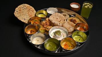 A traditional Indian meal with various dishes and chutneys on a metal plate.