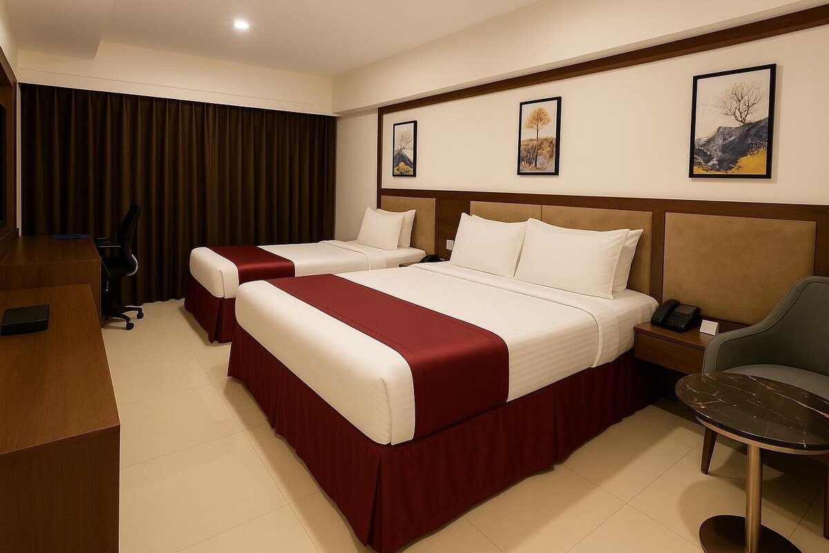 A hotel room with two beds, a desk, and a chair.