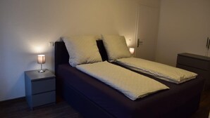 Een enkel bed met hoofdeinde, twee nachtkastjes en een bijzettafeltje.