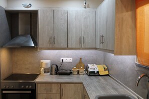 A compact kitchen with a stove, coffee maker, toaster, and a small refrigerator.
