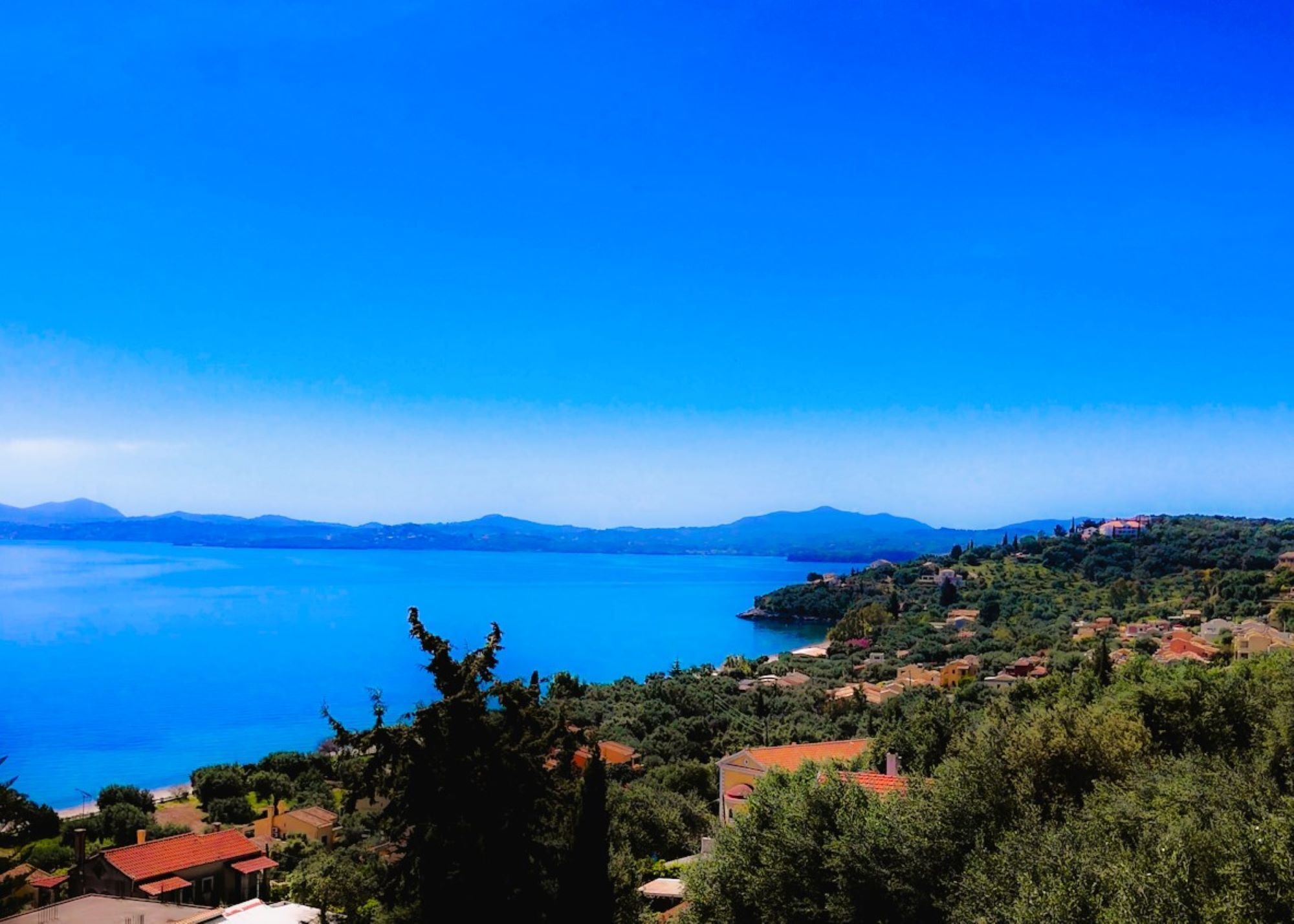 Un pueblo costero con vista al mar y montañas a lo lejos.