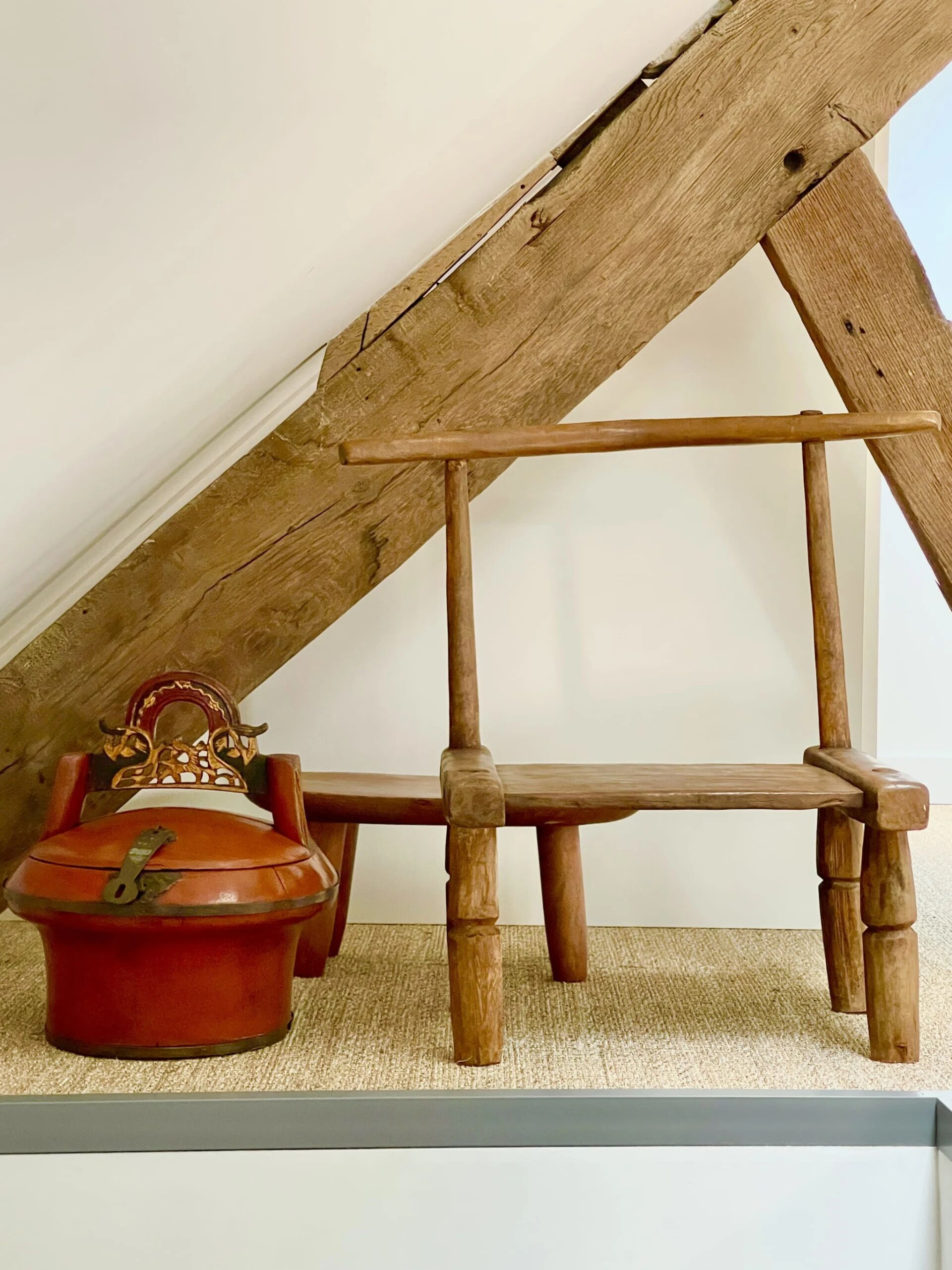 A rustic wooden chair and a small table in a room with sloped ceilings.