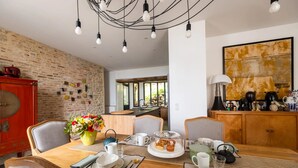 A dining area with a wooden table set for a meal, a red cabinet, and a brick wall. - Villa Figue Blanche (Montagny-lès-Buxy)