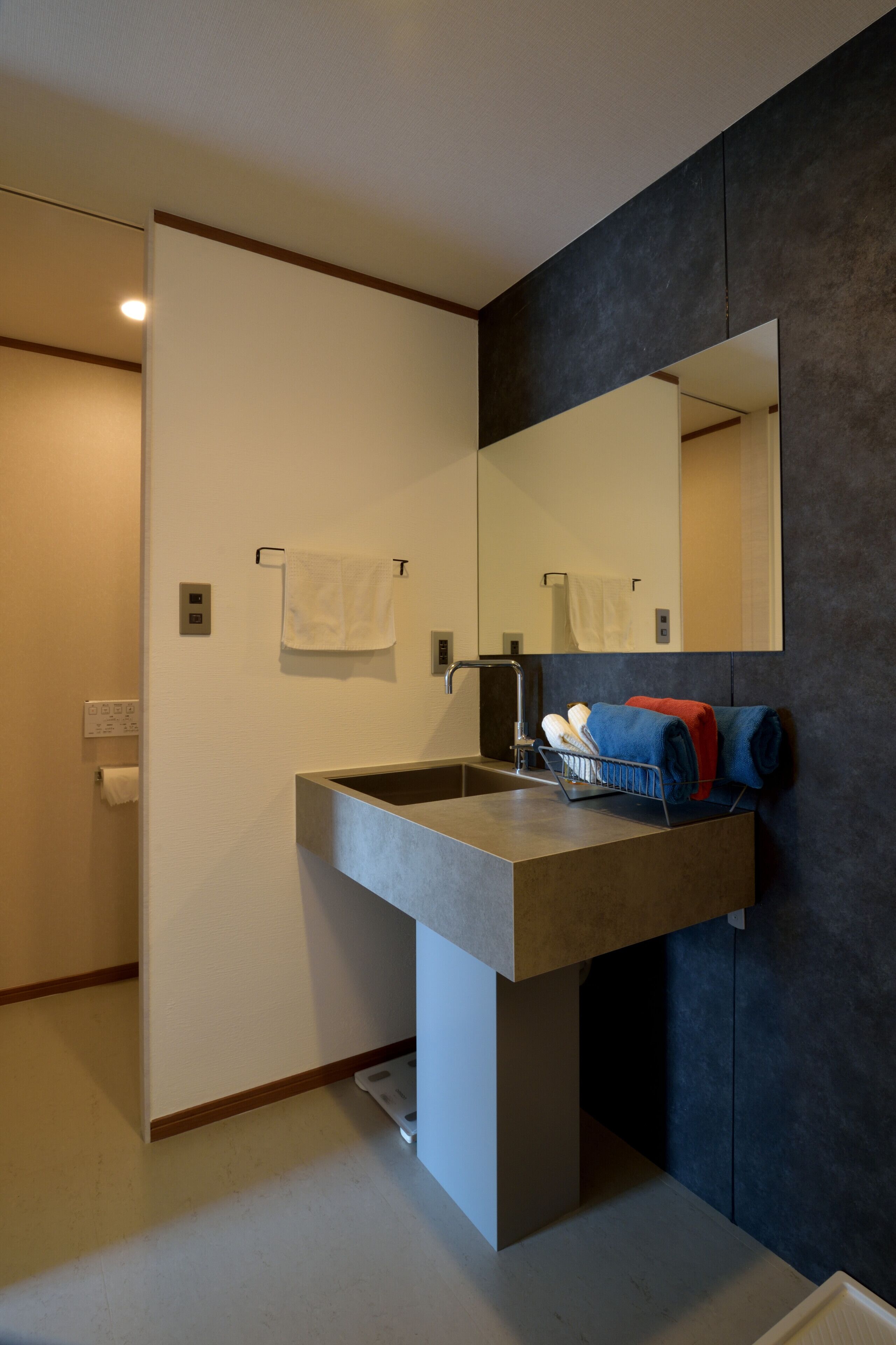 A modern bathroom with a large sink, a mirror, and towels on a rack.