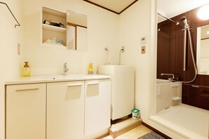 A bathroom with a sink, mirror, and shower.