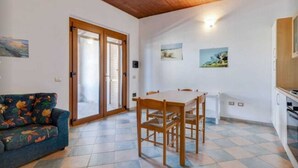Ein Zimmer mit Esstisch, Stühlen, einer Sitzecke und einer Küchenzeile.