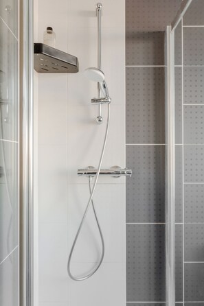 Eine moderne Dusche mit Duschbrause und Armaturen an der Wand.
