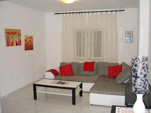 Un salon avec un canapé, une table basse et deux tableaux accrochés au mur.