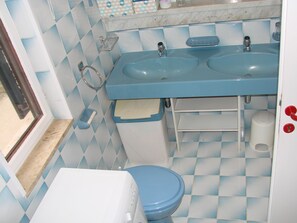 Une salle de bain avec deux lavabos, des toilettes et une fenêtre.