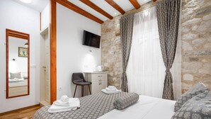 A bedroom with a bed, a desk, a chair, and a TV mounted on the wall. - Room-stephane City Vibe Suites - Double (Trogir)