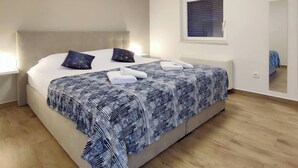 A neatly made bed with a patterned bedspread, two pillows, and a folded towel. - Basilea Superior Apartment (Malinska-Dubasnica)