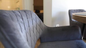 A modern, dark-colored sofa with a quilted backrest and a round wooden table beside it. - Basilea Superior Apartment (Malinska-Dubasnica)