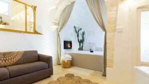 Un salon avec un canapé, une cheminée, un grand miroir et un mur en pierre.