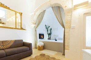 Uma sala de estar com sofá, lareira, um espelho grande e parede de pedra.