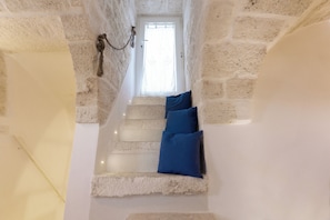 A stone staircase with blue cushions, a white door, and a light fixture.