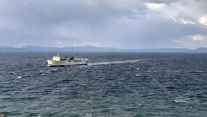 En båd på et stort vandareal med et bjergrigt landskab i baggrunden.