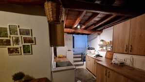 Una cocina con armarios de madera, piso de piedra y una zona de comedor con mesa y sillas.