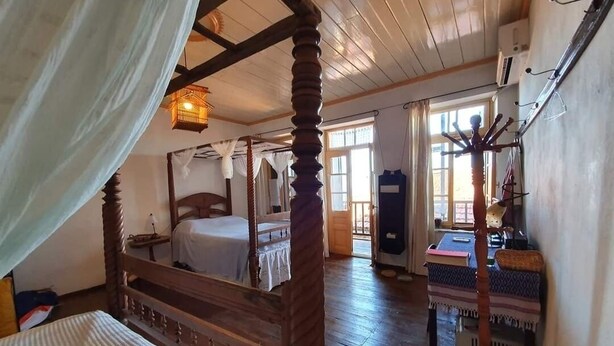 Una cama tradicional con dosel de madera y cuatro postes, suelo de madera y decoración rústica.
