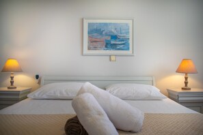 A hotel room with a bed, two bedside lamps, a painting on the wall, and a remote control on the nightstand. - Private Villa Agia Irini, 350 Meter to the Beach for 4 Guests With Pool Access! (Paros)