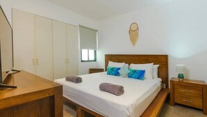A bedroom with a bed, a wooden nightstand, a desk, and a wardrobe. - One Bedroom Penthouse In The Exclusive Aldea Zama (Tulum)