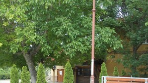 A building with a yellow facade, a red pole, and a bench. - Cozy Family Cottage at the Lake Balaton (Siófok)