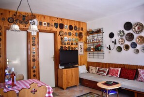 A cozy living room with a wooden wall adorned with various plates and a television on a wooden cabinet.