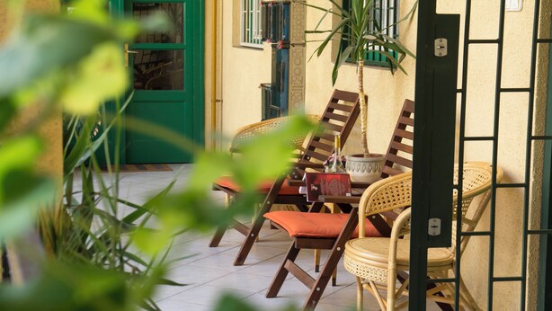 A patio area with wicker furniture and a green door. - Vibrant 3 Bedroom Apartment In The Pulsing Heart Of Budapest (Budapest)