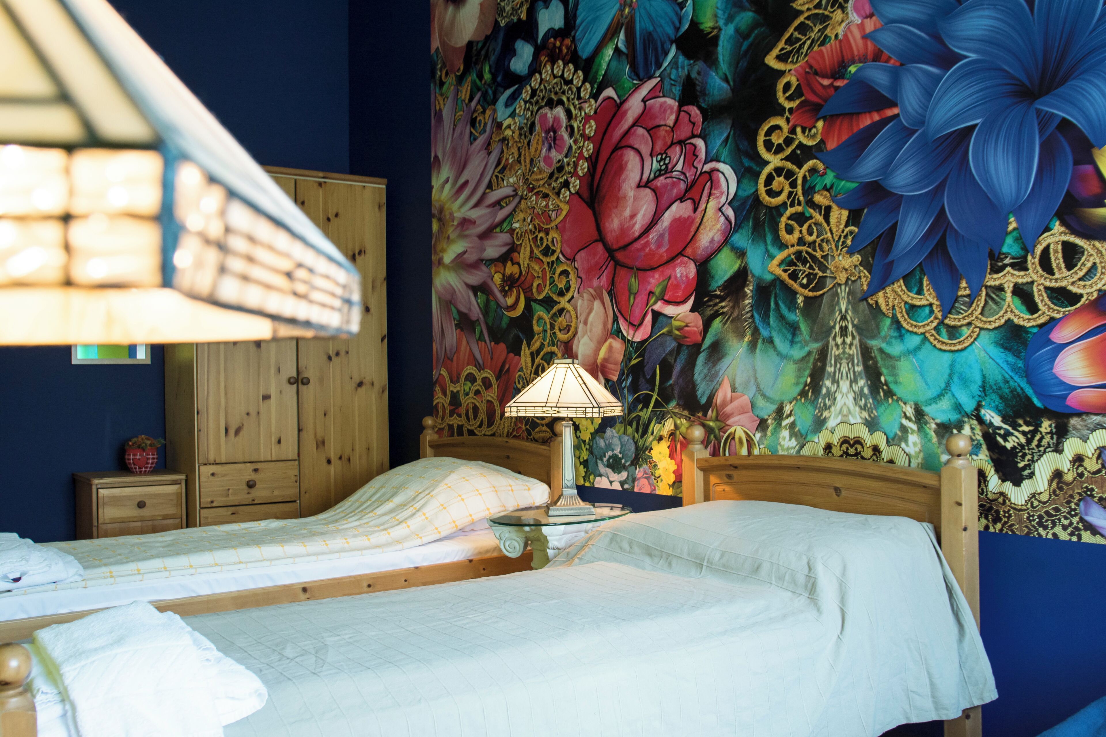 A bedroom with a bed, a nightstand, a lamp, and a wooden wardrobe.