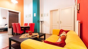 A brightly colored living room with a yellow sofa, red chairs, and a black coffee table. - Vibrant 3 Bedroom Apartment In The Pulsing Heart Of Budapest (Budapest)
