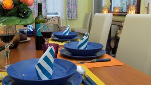 Una mesa de comedor dispuesta con platos azules, una botella de vino y un ramo de flores naranjas.