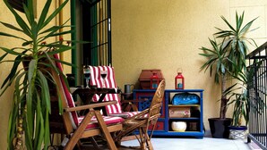 Un patio con sillas de mimbre, un mantel a rayas y plantas en macetas.
