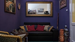 Una habitación con un sofá negro, un tablero de ajedrez, un jarrón decorativo y una estatua.