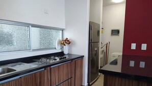 A modern kitchen with a gas stove, stainless steel sink, and a refrigerator.