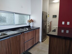 A modern kitchen with a gas stove, stainless steel sink, and a refrigerator.