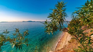 A coastal view with clear turquoise waters, a sandy beach, and rocky terrain. - "room in Guest Room - Room With Private Pool" (Corfu)