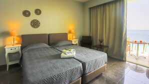A hotel room with a large bed, two bedside tables with lamps, a small table with a chair, and a view of the sea through a window with curtains. - "room in Guest Room - Room With Private Pool" (Corfu)
