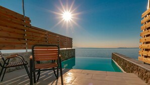 A wooden deck with a chair and a pool, overlooking a body of water. - "room in Guest Room - Room With Private Pool" (Corfu)