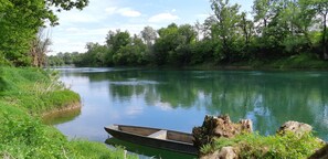 Een rustige rivier met een boot aangemeerd aan de linker oever, omringd door weelderige begroeiing en bomen.