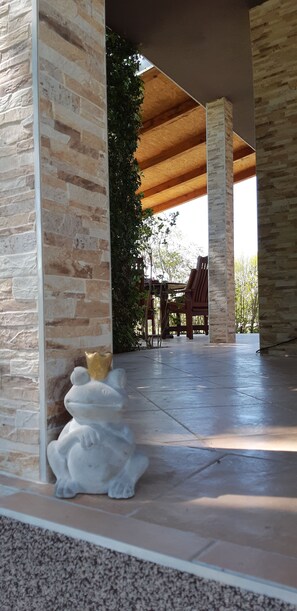 A covered outdoor area with stone pillars, a seating area, and a decorative frog statue. - Green Retreat Kuca uz Rijeku za Savrseni Odmor (Lekenik)