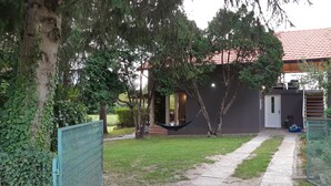 Une maison avec un toit recouvert de tuiles rouges, une terrasse couverte et un hamac dans le jardin.