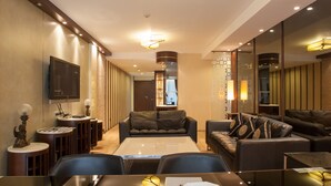 Ein modernes Hotelzimmer mit großem Flachbildfernseher, einer Couch, einem Esstisch und einem Couchtisch.