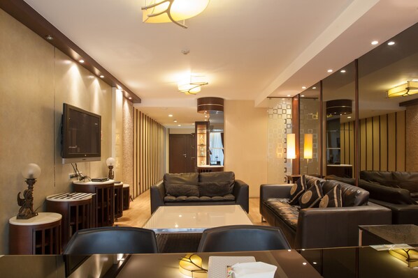 Una habitación de hotel moderna con un televisor de pantalla plana grande, un sofá, una mesa de comedor y una mesa de centro.