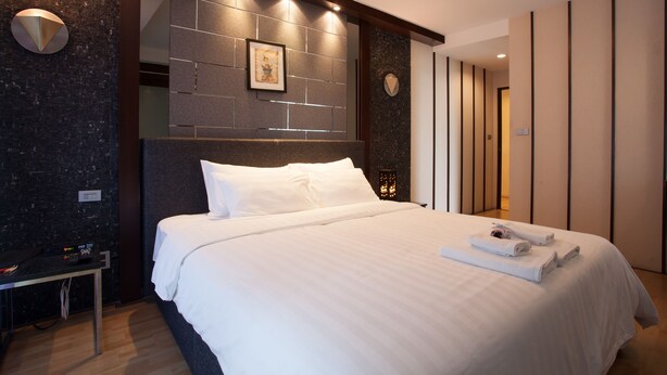 Ein modernes Hotelzimmer mit einem großen Bett, einem Nachttisch und einem an der Wand hängenden Kunstwerk.