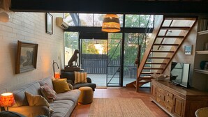Un salon confortable avec un canapé, un téléviseur et un escalier menant à l’étage supérieur.