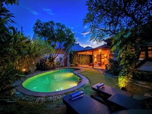 Una piscina envoltada de gandules i un porxo cobert amb vista al cel.