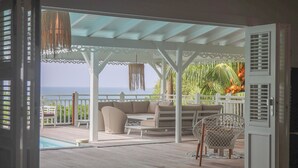 En åben patio med havudsigt, en hvid pergola og udendørs møbler.