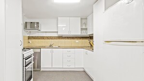 A compact kitchen with white cabinets, a microwave, a stove, and a dishwasher. - Alpine Heights 11B - Mt Hotham (Hotham Heights)